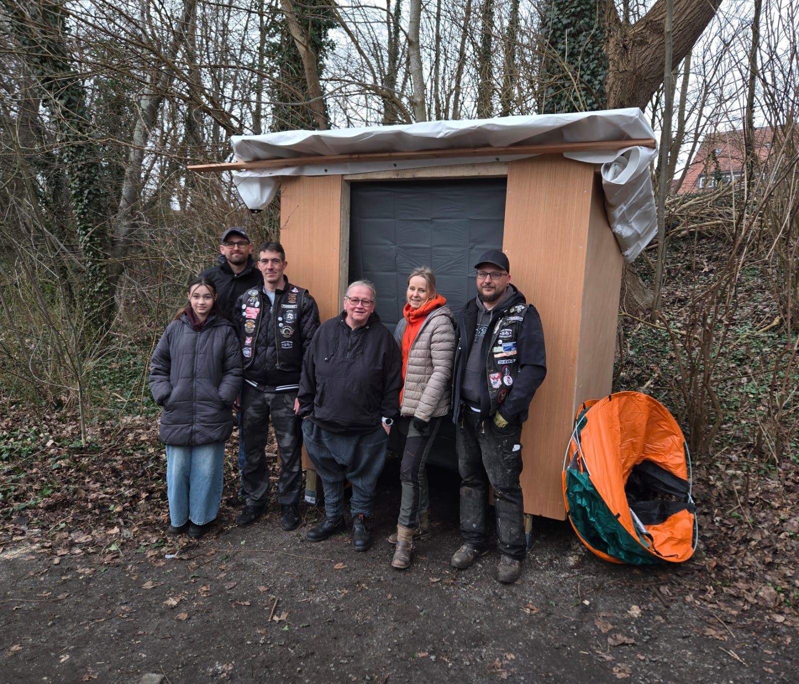 Sechs Personen stehen vor der eingerüsteten Schutzhütte mit Notzelt